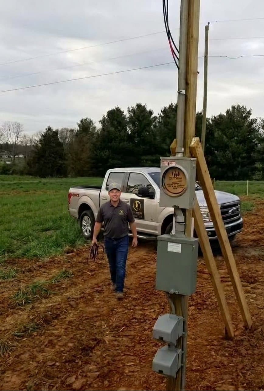 VoltWise electrician walking past a newly set temporary power pole with meter base, disconnect and outlets